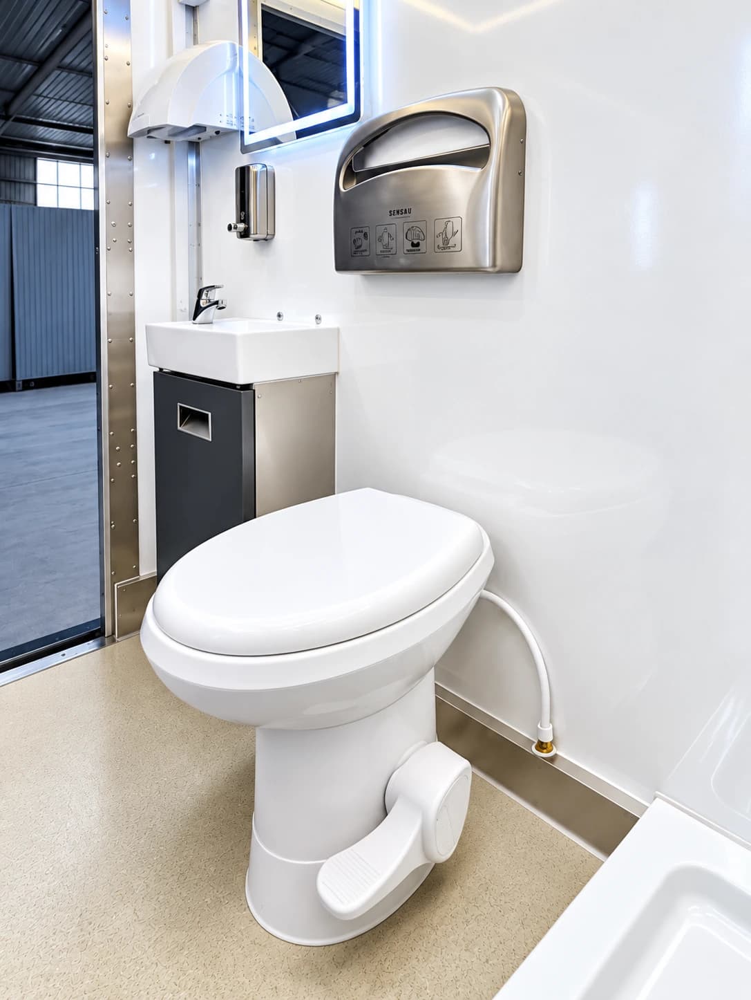 Restroom trailer interior with a toilet and handwashing sink